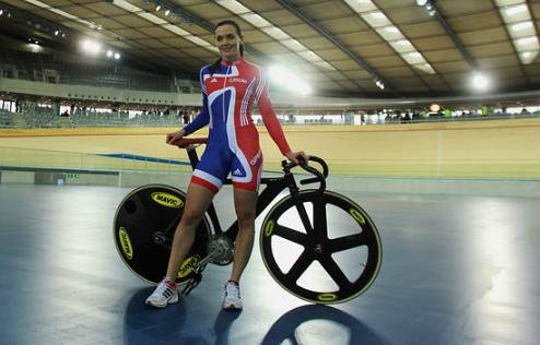 Track cyclists racing at speed on the banked curve of an indoor velodrome