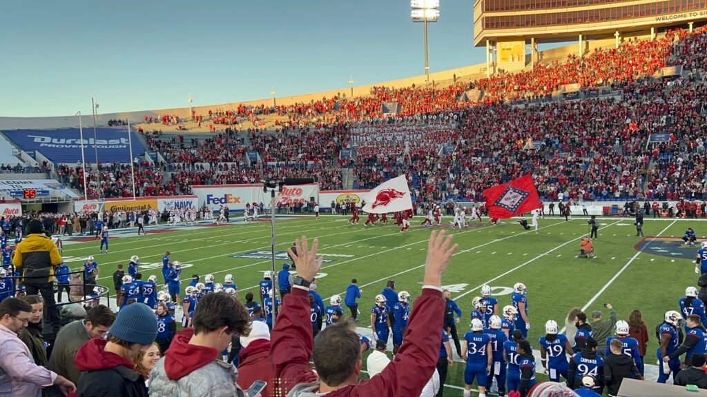 Arkansas Razorbacks players and coaches on the sideline during an SEC football game.